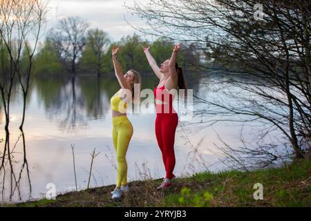Zwei Erwachsene Frauen in hellen Trainingsanzügen spielen draußen Sport. Stockfoto