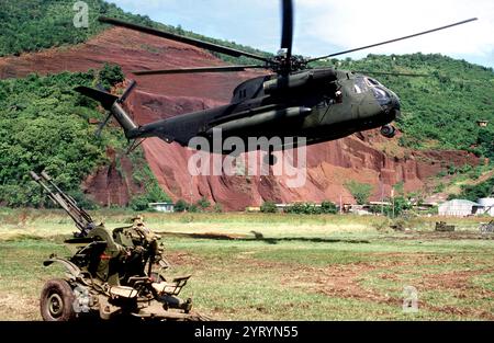 Der Seehengst-Helikopter Sikorsky CH-53D des U.S. Marine Corps schwebt über dem Boden in der Nähe einer sowjetischen ZU-23-Flugabwehrwaffe, bevor er sie während der Operation Urgent Fury, der US-Invasion von Grenada im Oktober 1983, abhebt. Stockfoto