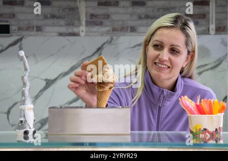 Trier, Deutschland. Dezember 2024. Die Eigentümerin der Eisdiele Svetlana Novoselska arrangiert in der Adventszeit ein Spekuloos-Eis auf einer Schaufel Tiramisu. Ihr Geschäft ist auch im Winter geöffnet und bietet Waffeln, crêpes, Kuchen und heiße Getränke. Quelle: Harald Tittel/dpa/Alamy Live News Stockfoto