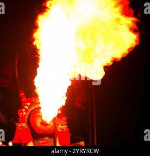 Chinesischer Feuerwehrmann. Feuer essen ist der Akt, ein brennendes Objekt in den Mund zu stecken und zu löschen. Ein Feuerfresser kann ein Entertainer, ein Straßenkünstler, Teil einer Sideshow oder einer Zirkusvorstellung sein, ist aber auch Teil der spirituellen Tradition in Indien. Stockfoto