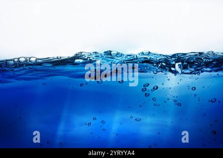 Wasserblasen schweben unter Wasser auf weißem Hintergrund. Ruhiges Meer unter blauem Himmel bei Sonnenaufgang. Wasserlinie. Seewasseroberfläche. Blauer Wasserspritzer Stockfoto