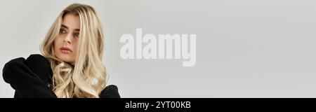 Schöne junge Frau mit langen blonden Haaren trägt elegante schwarze Kleidung in einem modernen Studio, Banner Stockfoto