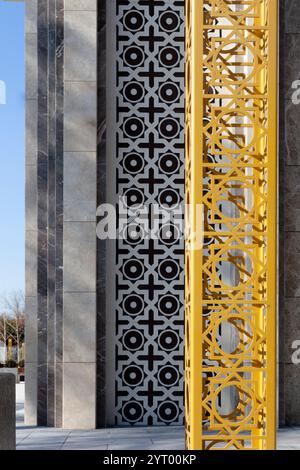 Blick auf den Rand der Außenwand des Gebäudes mit Ornamenten an der Wand und gelber Metallstruktur in der Nähe des Hauses. Stockfoto