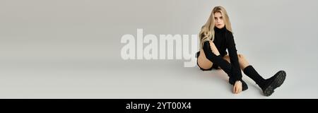 Eine atemberaubende junge Frau sitzt anmutig in einem schwarzen Outfit, strahlt Vertrauen und Stil aus Stockfoto