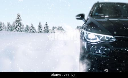Das schwarze Auto fährt durch den Schnee. Räder mit Winterreifen im Schnee auf dem Hintergrund eines Winterwaldes, Konzept. Winterreifen, kreative Idee. Stockfoto