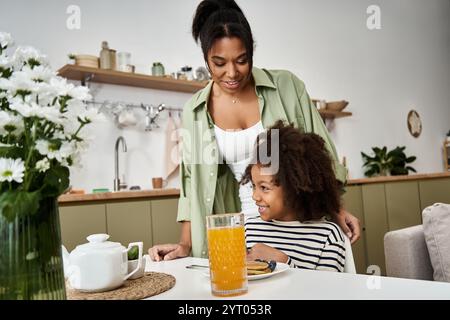 In einer gemütlichen Küche frühstücken Mutter und Tochter voller Lächeln und Lachen. Stockfoto