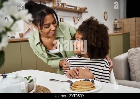 Mutter und Tochter teilen einen freudigen Moment, während sie zusammen Pfannkuchen genießen. Stockfoto