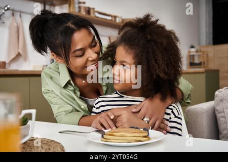 Mutter und Tochter teilen einen warmen und liebevollen Moment beim Frühstück in ihrem gemütlichen Zuhause. Stockfoto