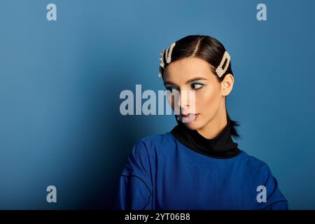 Eine modische junge Frau zeigt ihre trendige Kleidung, während sie im Studio posiert. Stockfoto