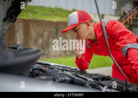 Ein junger Mechaniker inspiziert Motorteile und zeigt Leidenschaft für Ingenieurskunst Stockfoto