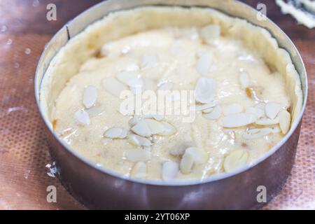Rohe Apfeltorte mit Mandelblättern in einer Auflaufform auf dem Produktionstisch. Hochwertige Fotos Stockfoto