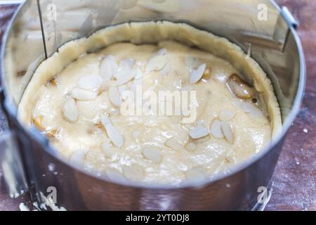 Rohe Apfeltorte mit Mandelblättern in einer Auflaufform auf dem Produktionstisch. Hochwertige Fotos Stockfoto