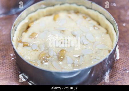 Rohe Apfeltorte mit Mandelblättern in einer Auflaufform auf dem Produktionstisch. Hochwertige Fotos Stockfoto