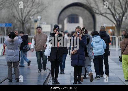 (241205) -- PEKING, 5. Dezember 2024 (Xinhua) -- Touristen aus Deutschland machen Fotos in der Qianmen Straße in Peking, Hauptstadt Chinas, 4. Dezember 2024. Die Ausweitung der visafreien Politik ist ein Meilenstein auf Chinas Weg zu größerer Offenheit und zeigt auch sein Vertrauen auf der globalen Bühne. Bisher genießen 38 Länder einseitigen visafreien Zugang, und der maximale Aufenthalt für Besucher wurde ab November 30 auf 30 Tage verlängert. Im dritten Quartal 2024 erreichte die Zahl der Ausländer, die nach China einreisten, 8,186 Millionen, was einem Anstieg von 48,8 Prozent gegenüber dem Vorjahr entspricht. Unter ihnen sind 4,885 Millionen von ihnen visafreie Einreise nach China, ein Jahr vor Stockfoto