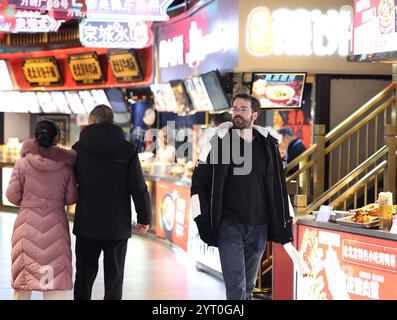 (241205) -- PEKING, 5. Dezember 2024 (Xinhua) -- Ein ausländischer Tourist besucht die Dashilan Handelsstraße in Peking, Hauptstadt Chinas, 5. Dezember 2024. Die Ausweitung der visafreien Politik ist ein Meilenstein auf Chinas Weg zu größerer Offenheit und zeigt auch sein Vertrauen auf der globalen Bühne. Bisher genießen 38 Länder einseitigen visafreien Zugang, und der maximale Aufenthalt für Besucher wurde ab November 30 auf 30 Tage verlängert. Im dritten Quartal 2024 erreichte die Zahl der Ausländer, die nach China einreisten, 8,186 Millionen, was einem Anstieg von 48,8 Prozent gegenüber dem Vorjahr entspricht. Unter ihnen sind 4,885 Millionen von ihnen visafreie Einreise nach China, ein Jahr vor Stockfoto