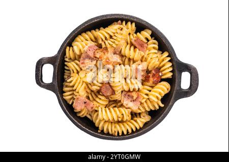 Fusilli köstliche Carbonara-Pasta mit knusprigen Speckstückchen und frischen Kräutern in einer Pfanne isoliert auf weißem Hintergrund. Stockfoto