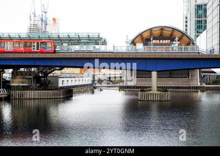 DLR-Zug überquert die Eisenbahnbrücke North Dock und Blick auf das Big Easy Restaurant am Canary Wharf West India Quay East London England 2024 UK KATHY DEWITT Stockfoto