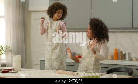 Glückliche afroamerikanische Familienfrau weibliche Mutter Mutter Mutter zusammen macht Spaß in der Küche kleines Kind Kind Mädchen Tochter tanzt Musik tanzen in Stockfoto