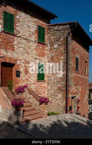 Rote Ziegelsteine und grüne Fensterläden: Alte Häuser in der toskanischen Stadt Lucignano, Italien. Stockfoto