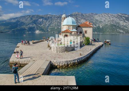 Die katholische Inselkirche „unsere Lieben Frau der Felsen“ befindet sich an der berühmten Bucht von Kotor in Montenegro mit einem Touristen im Vordergrund. Stockfoto
