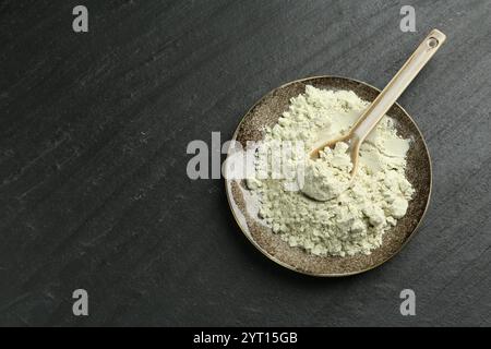 Teller mit trockenem Wasabi-Pulver und Löffel auf dunkel strukturiertem Tisch, Draufsicht. Leerzeichen für Text Stockfoto