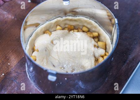 Rohe Apfeltorte mit Mandelblättern in einer Auflaufform auf dem Produktionstisch. Hochwertige Fotos Stockfoto