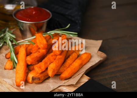 Süßkartoffelfritten, Rosmarin und Ketchup auf Holztisch, Nahaufnahme Stockfoto