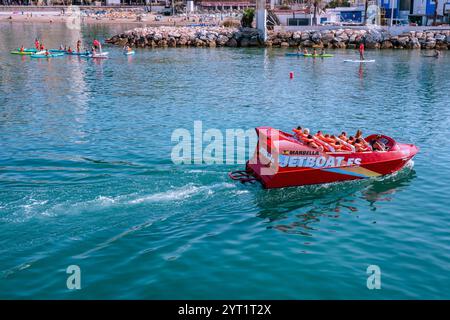 Touristen, die mit einem Schnellboot im Meer in der Nähe eines Strandes in marbella, spanien, fahren und ein aufregendes Wassererlebnis genießen Stockfoto