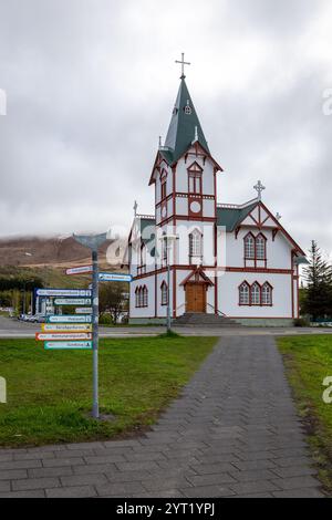 Husavik, Island, 21.05.22. Husavik Holzkirche (Husavikurkirkja) in Husavik, Island mit farbenfrohen Wegweisern zu Touristenattraktionen. Stockfoto