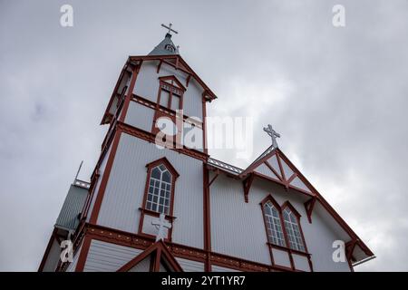 Husavik Holzkirche (Husavikurkirkja) in Husavik, Island. Kirche mit weißer Holzfassade und rotem Rahmen vor bewölktem Himmel, geringer Blickwinkel. Stockfoto
