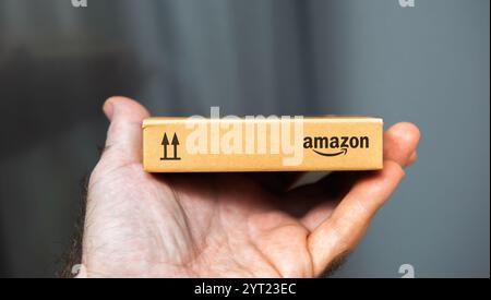 Paris, Frankreich – 22. November 2021: Nahaufnahme einer Hand mit einem kleinen Karton mit Amazon-Markenzeichen, das die kompakte Größe und das minimalistische Verpackungsdesign in einem klaren Hintergrund zeigt Stockfoto