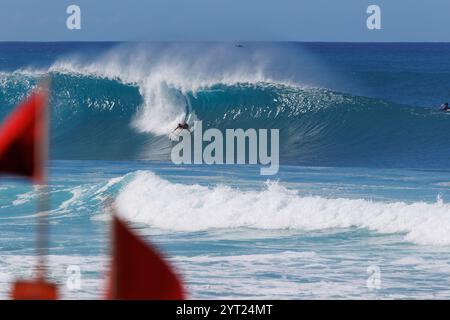 November 30 2024, Pupukea, Hawaii. Ein Surfer stürzt mit roten, hohen Brandwarnflaggen am Strand an der Nordküste von Oahu in eine Welle. Stockfoto