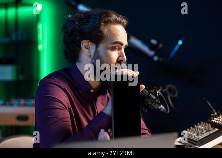 Ein technischer Spezialist präsentiert ein Tablet im Einstiegssegment für niedrige Budgets für interessierte Zuschauer und filmt im Studio. Viraler Content Creator, der digitale Geräte vor dem Internet-Publikum überprüft Stockfoto