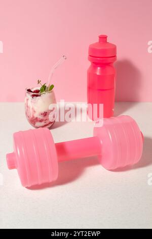 Obstjoghurt mit Himbeeren und Mentha im Glas, rosa Hantel und eine Flasche Wasser. Das Konzept des gesunden Lebens Stockfoto