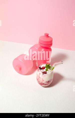 Obstjoghurt mit Himbeeren und Mentha im Glas, rosa Hantel und eine Flasche Wasser. Das Konzept des gesunden Lebens Stockfoto