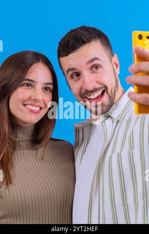 Paare machen Selfie zusammen mit Smartphone auf blauem Hintergrund. Vertikal Stockfoto