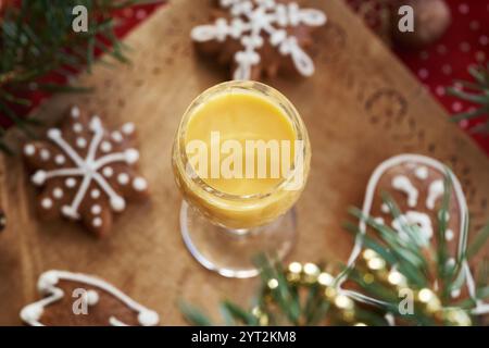 Ein Glas Eiecognac mit Lebkuchenweihnachtskeksen auf einem Holztisch Stockfoto