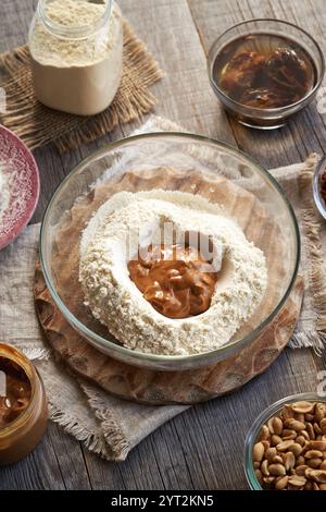 Molkenproteinpulver, Erdnussbutter und eingeweichte Datteln – Zutaten für hausgemachte Eiweißschokoladentafeln auf einem Tisch Stockfoto