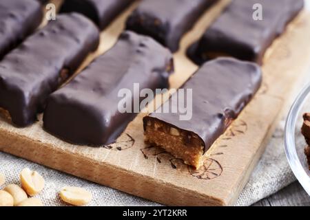 Hausgemachte, gesunde Tische aus Molkenproteinpulver, Datteln und Erdnussbutter, die mit Schokolade überzogen sind Stockfoto