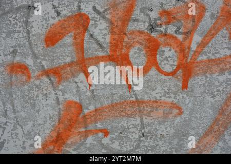 Zeichnungen, Graffiti, Inschriften auf einem alten Stahlbetonzaun, Ziegelmauern. Ungewöhnlicher Text, orangefarbene Signatur mit Sprühfarbe. Stockfoto