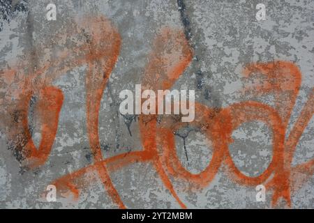 Zeichnungen, Graffiti, Inschriften auf einem alten Stahlbetonzaun, Ziegelmauern. Ungewöhnlicher Text, orangefarbene Signatur mit Sprühfarbe. Stockfoto