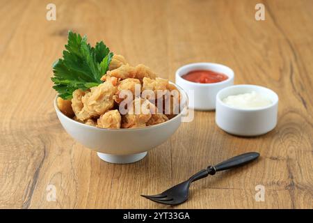 Eine Schüssel leckeres knuspriges hausgemachtes Hühnerpopcorn mit Mayonaise und Tomatensauce Stockfoto