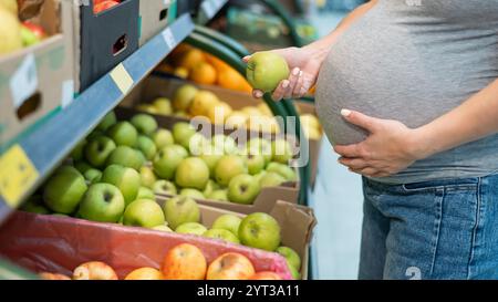 Schwangere Frau wählt Äpfel im Laden. Stockfoto