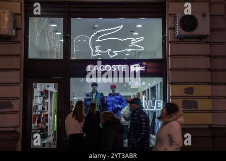 BELGRAD, SERBIEN - 12. OKTOBER 2024: Logo von Lacoste in ihrem Hauptgeschäft für Belgrad bei Nacht. Lacoste ist ein französisches Bekleidungsunternehmen, das Kleidung verkauft. Stockfoto