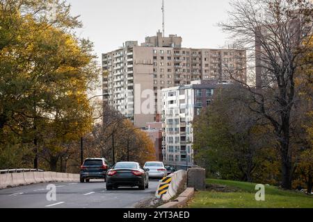 Stadtstraße in Montreals Cote des Neiges im Herbst, auf der vorbeifahrende Fahrzeuge mit Wohngebäuden im Hintergrund gezeigt werden. Ein Blick hinein Stockfoto