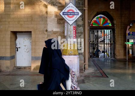 Eine muslimische Frau mit schwarzem Hijab, die auf einem Bahnsteig am Chhatrapati Maharaj Terminal (CSMT), dem geschäftigsten Bahnhof in Mumbai, Indien, läuft Stockfoto