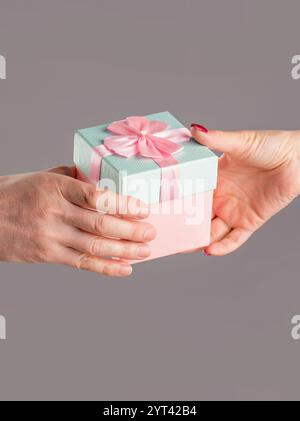 Geschenkbox in der Hand, Überraschung und Urlaubskonzept. Mannhände halten Valentinstag Geschenk. Das Mädchen gibt dem Mann ein Geschenk. Frauenhände, die Geschenk halten Stockfoto