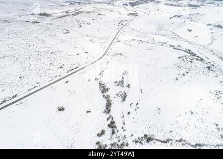 Schneebedeckte Bergstraße von oben, ein winterliches Wunderland. Luftperspektive einer Bergstraße, die sich durch Schnee schlängelt Stockfoto