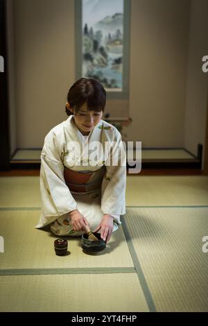 Eine junge Frau trinkt grünen Tee im Kimono Stockfoto