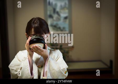 Eine junge Frau trinkt grünen Tee im Kimono Stockfoto